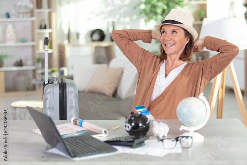 laid-back older woman with laptop globe and piggybank