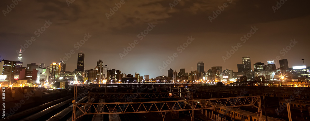 Naklejka premium Night time view of commuter trains under Nelson Mandela Bridge in Braamfontein Johannesburg CBD