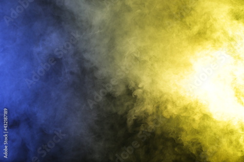 Artificial smoke in blue yellow light on black background