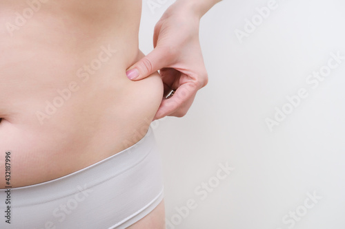 Fat belly of a woman. female hand of excessive fat on the belly.