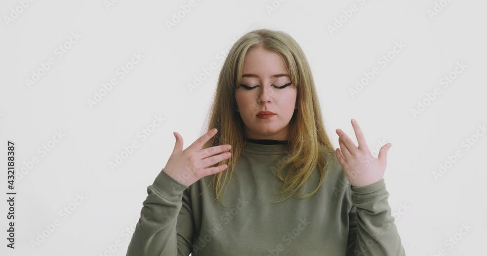 Tranquil plump woman in green clothes breathes and meditates posing for camera on white at audition close view slow motion Tranquil plump woman in green clothes breathes and meditates posing for camera on white at audition close view slow motion