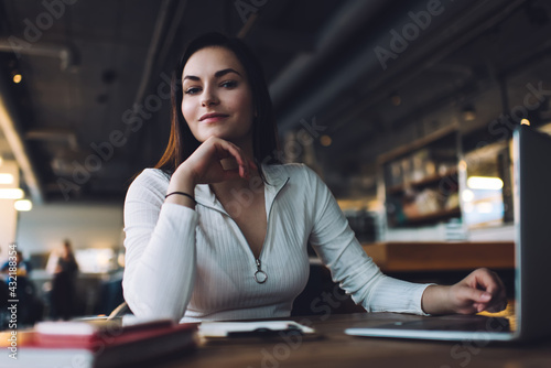 Smiling woman with hand at chin in cafeteria