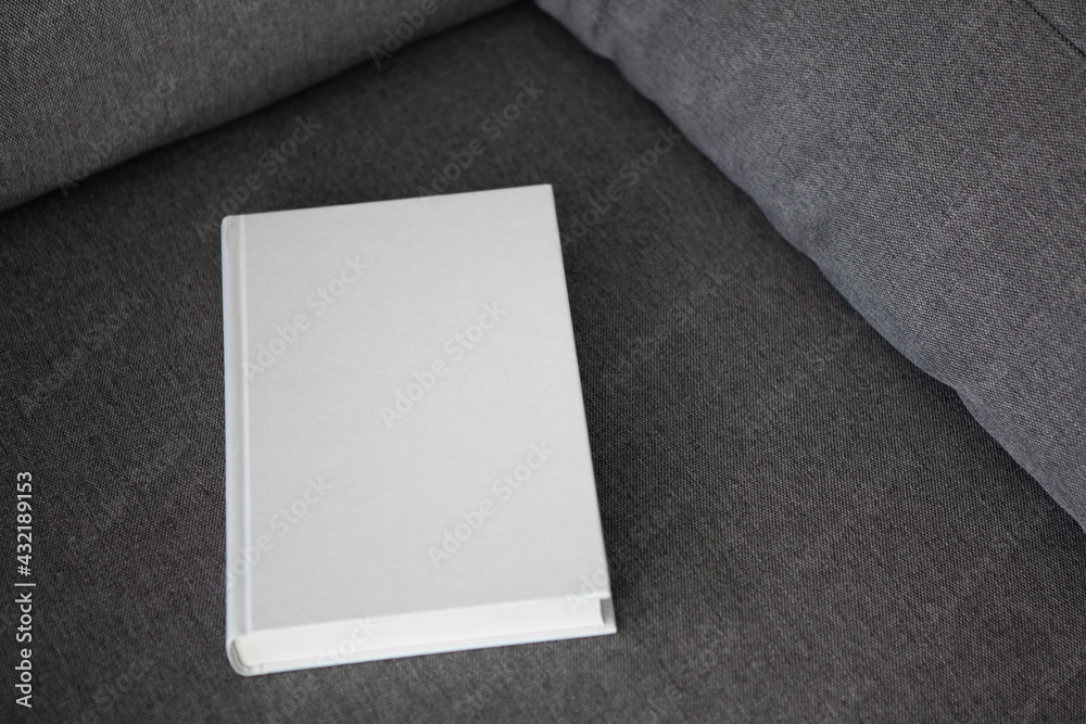 Book with blank cover and empty cover on a gray sofa Book with blank cover and empty cover on a gray sofa