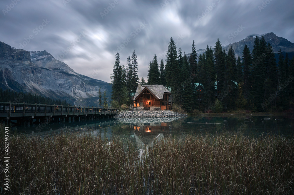 Wooden cottage glowing with pine forest and bridge reflection on Emerald lake at Yoho national
