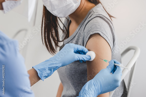 People getting a vaccination to prevent pandemic concept. Woman in medical face mask  receiving a dose of immunization coronavirus vaccine from a nurse at the medical center hospital