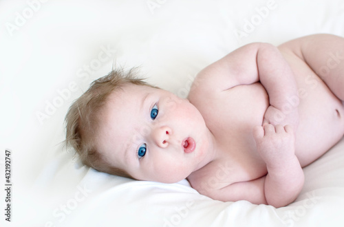 Cute happy 3 month baby boy lying on a white sheet