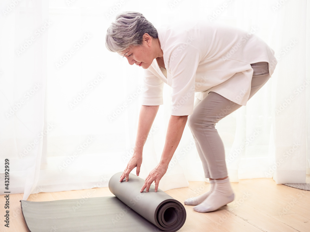 Senior asian woman exercise at home health care holding yoga mat