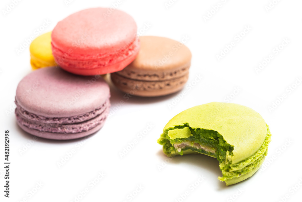 Bitten macaron and Various flavors of pastel macarons stacked against isolated on white background. Macarons is a delicate meringue-based cookie sandwich It is a dessert of French origin. Bitten macaron and Various flavors of pastel macarons stacked against isolated on white background. Macarons is a delicate meringue-based cookie sandwich It is a dessert of French origin.