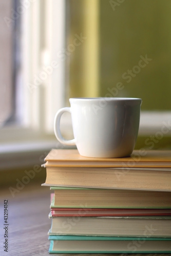 Stack of hardcover books and a cup of tea or coffee. Selective focus.