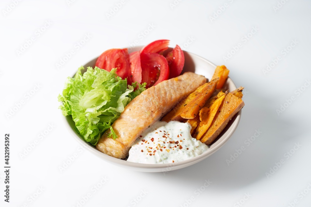 Bowl with baked salmon, sweet potatoes, tomatoes, fresh salad and Greek yogurt