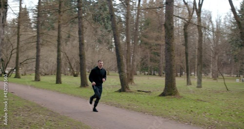 A young man in sportswear runs against the background of trees.