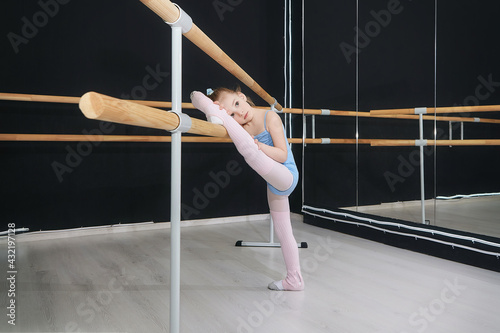 little girl does exercises in the hall of the choreographic school with a ballet barre
