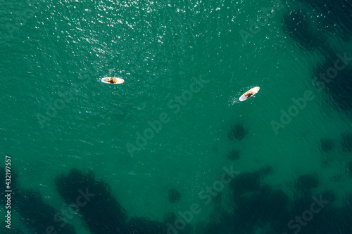 Two stand up paddle boarders in the sea at Porthcurno beach, west Cornwall