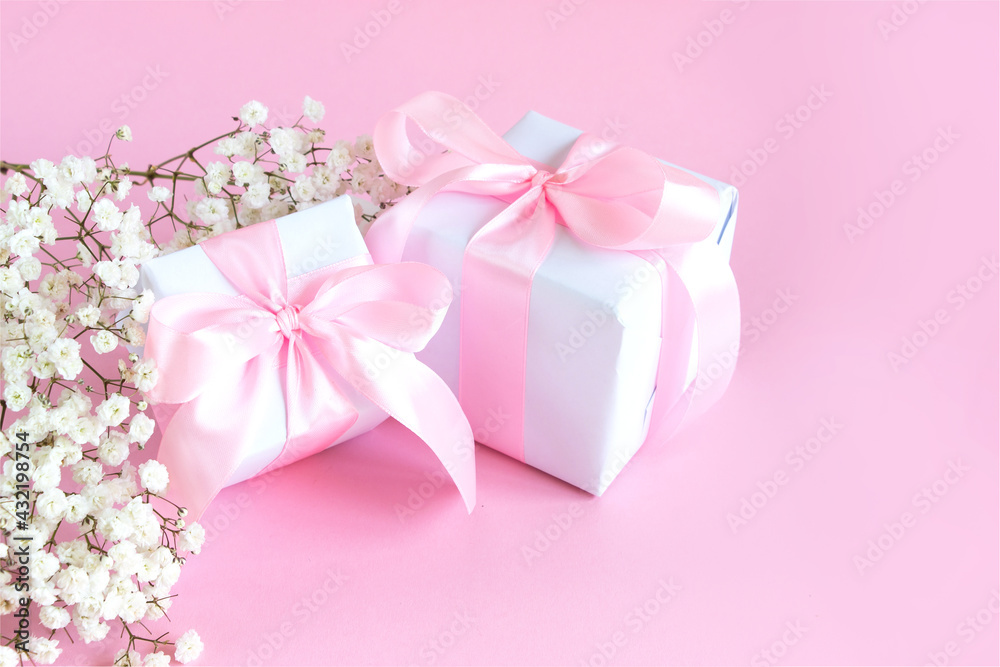 Gift box and a bouquet of blooming gypsophila on a pink background. Mother's day holiday concept. Copy space.