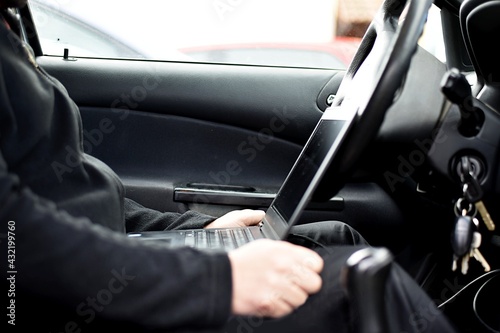 A man sits in the car and does diagnostics on a laptop