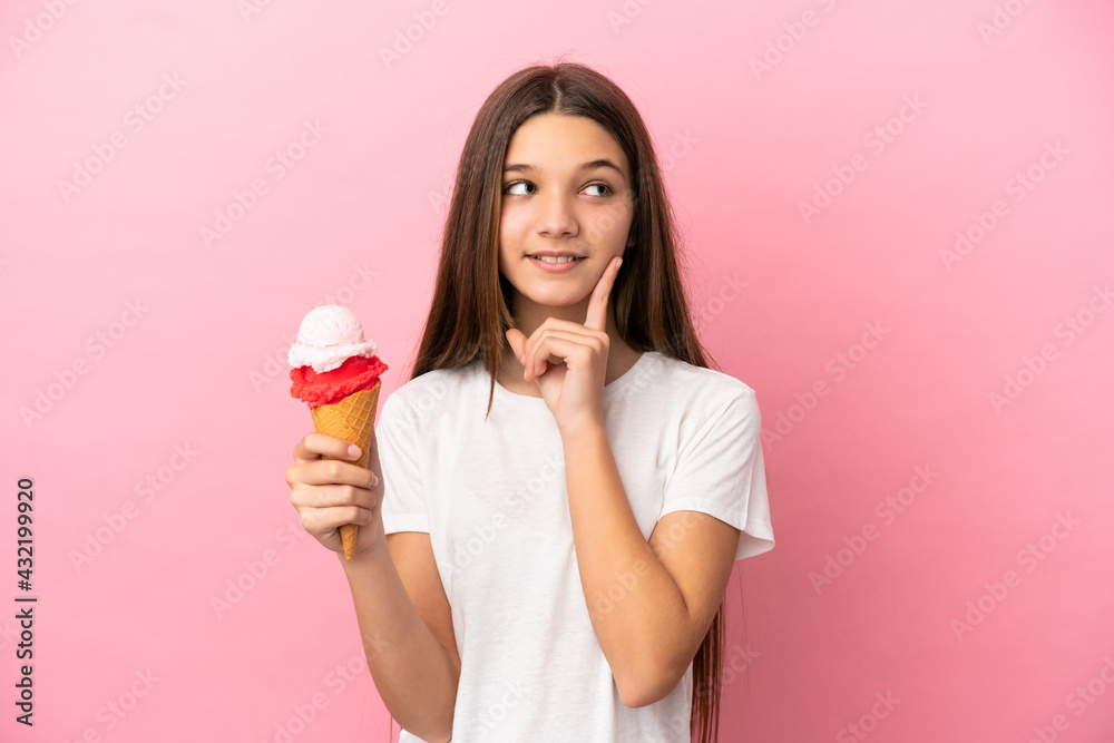 Little girl with a cornet ice cream over isolated pink background thinking an idea while looking up Little girl with a cornet ice cream over isolated pink background thinking an idea while looking up
