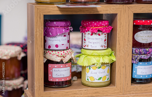 Jam, Curd and Honey jars for sale on a shelf at a fayre with colourful lid decoration photo