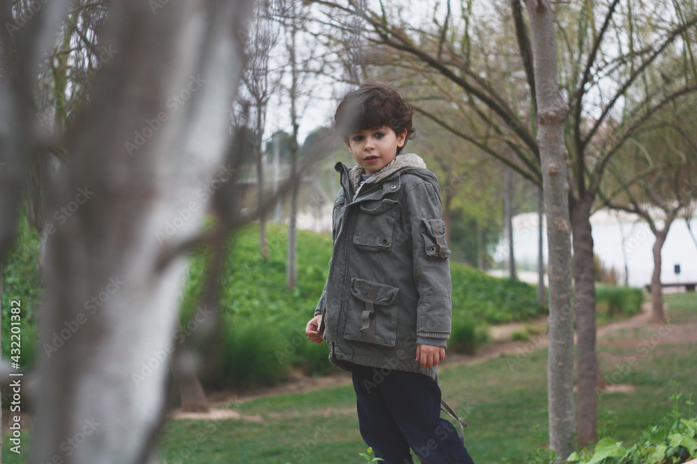 Spanish boy with jacket, walking and enjoying nature in a green forest Spanish boy with jacket, walking and enjoying nature in a green forest