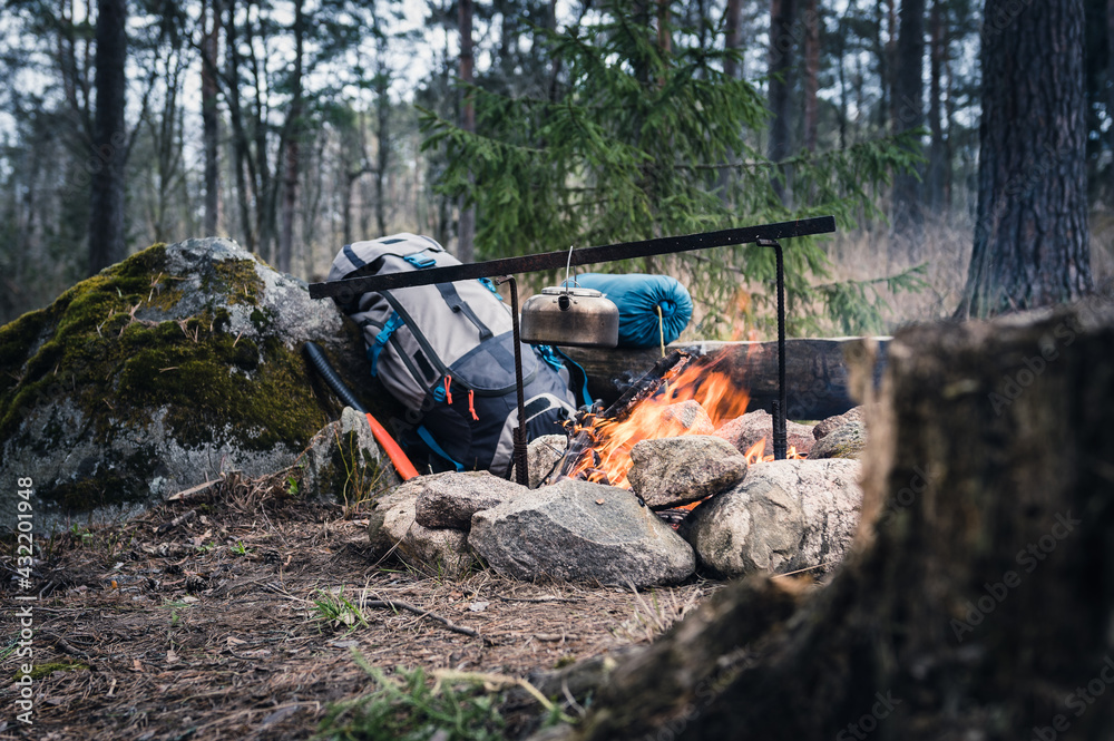 Backpack and Metal kettle on a campfire in the forest Backpack and Metal kettle on a campfire in the forest