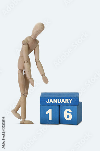 day of the month 16 January calendar . A calendar date on blue cubes and a wooden man standing next to it. White background