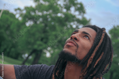 Portrait of a man looking at the sky outside in nature in the spring time