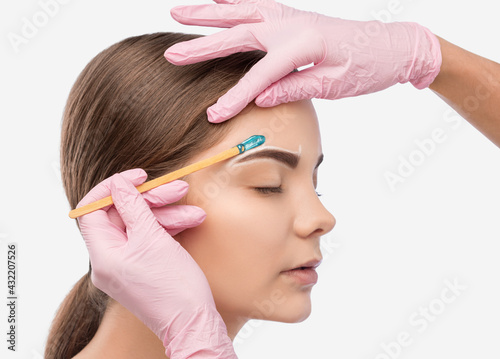 Makeup artist does facial hair removal procedure. Beautiful girl with blue eyes having Permanent Make-up on her Eyebrows. Professional makeup.