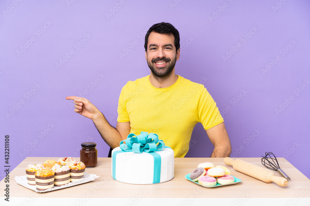 Man in a table with a big cake pointing finger to the side Man in a table with a big cake pointing finger to the side
