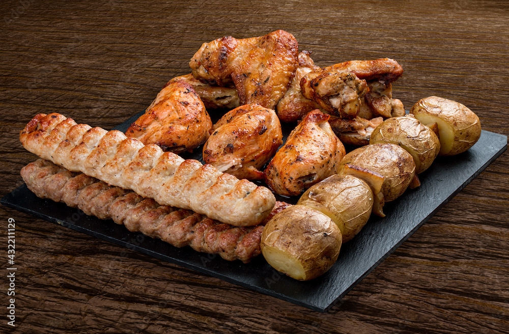Stone board with different tasty cooked meat on wood background. Assorted meat Stone board with different tasty cooked meat on wood background. Assorted meat