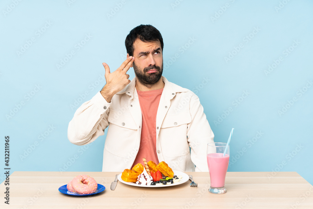 Man at a table having breakfast waffles and a milkshake with problems making suicide gesture