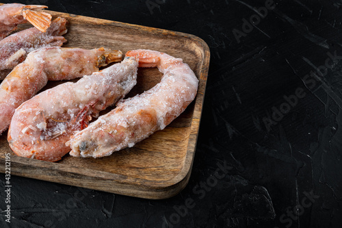 Frozen red Argentinian prawns, on wooden tray, on black background , with copyspace and space for text