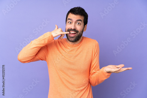 Caucasian handsome man over isolated purple background making phone gesture and doubting