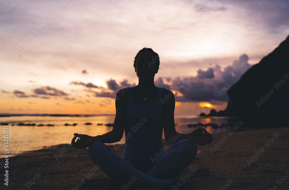 Anonymous woman meditating during sundown - obrazy, fototapety, plakaty 