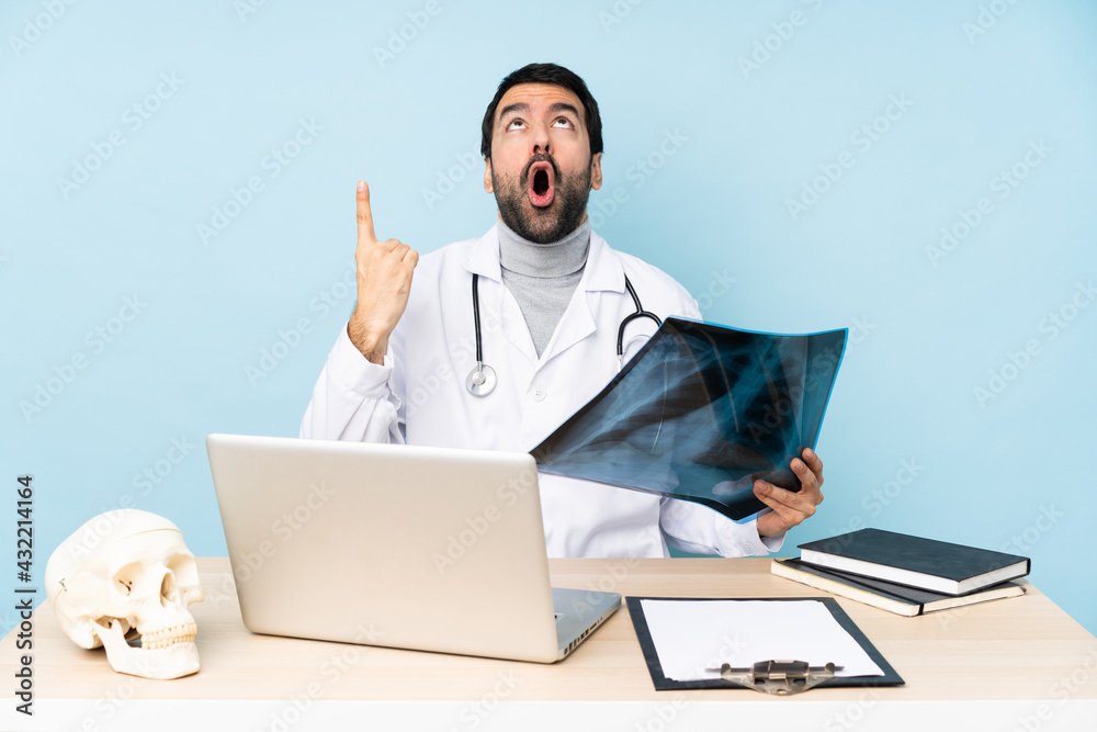 Professional traumatologist in workplace surprised and pointing up Professional traumatologist in workplace surprised and pointing up