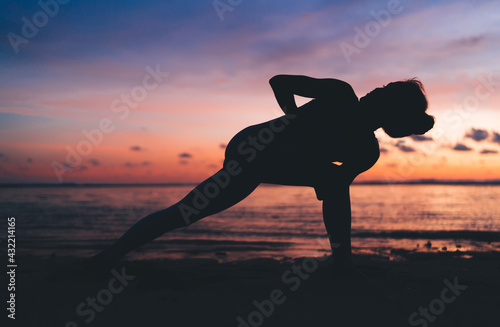 Flexible woman doing yoga on beach