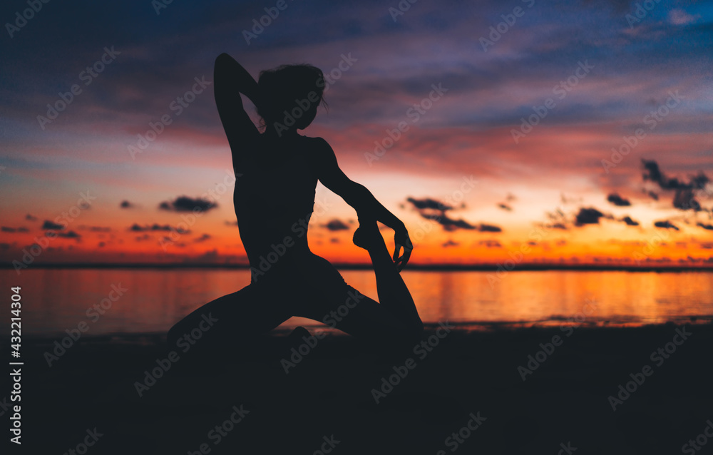 Unrecognizable lady performing yoga on seaside at sundown
