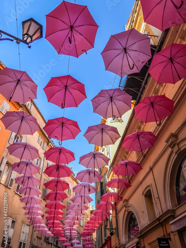 Ombrelles roses décorant une ruelle aux couleurs chaudes