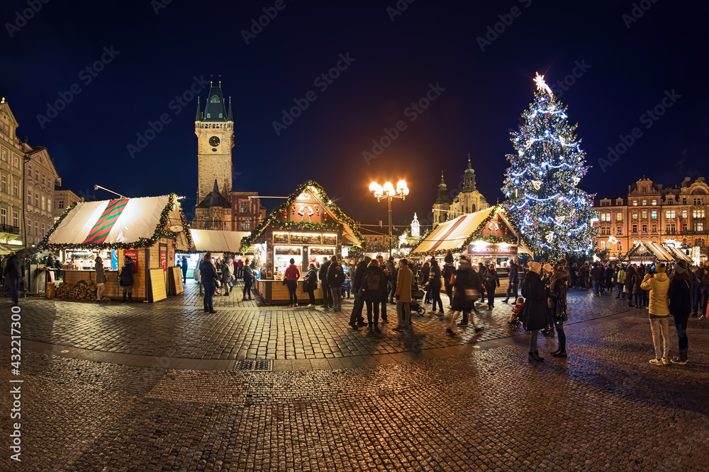 Prague, Czech Republic. Panoramic view of Christmas market at Old Town Square with the city's main Christmas tree in dusk. The Old Town Hall and St. Nicholas Church are visible in the background.
