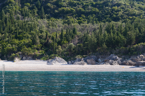 Turquoise sea, wild pebble beach and rocks surrounded by vegetation, Albania. Travel and vacation theme