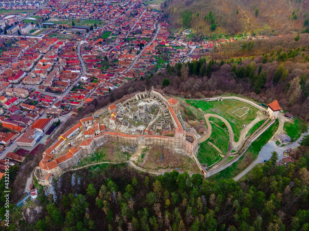 Aerial photography of medieval fortification at Rasnov city in Brasov county, Romania. Top view of the citadel with Rasnov city down below. Drone shot of Rasnov medieval citadel. Aerial photography of medieval fortification at Rasnov city in Brasov county, Romania. Top view of the citadel with Rasnov city down below. Drone shot of Rasnov medieval citadel.