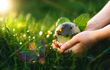 Hands holding crystal earth globe in sunny green grass.  Environment, save clean planet, ecology concept. Earth Day banner with copy space.
