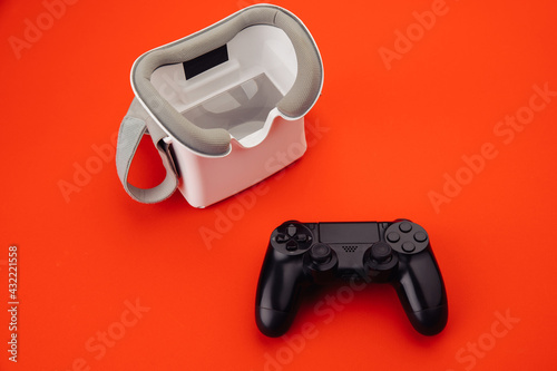 Gaming concept. VR virtual reality glasses with back gamepad on red background