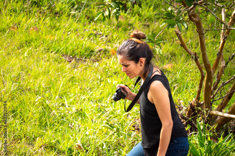 Young Short Hispanic Woman in Blue Jeans and Black Shirt Takes Picture with Compact Mirrorless Camera Young Short Hispanic Woman in Blue Jeans and Black Shirt Takes Picture with Compact Mirrorless Camera