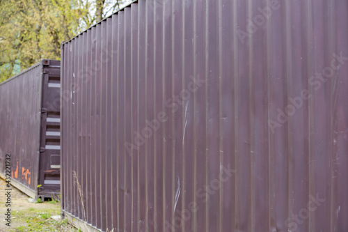 Old 40-foot shipping containers are abandoned and lined up in a street dump during the day