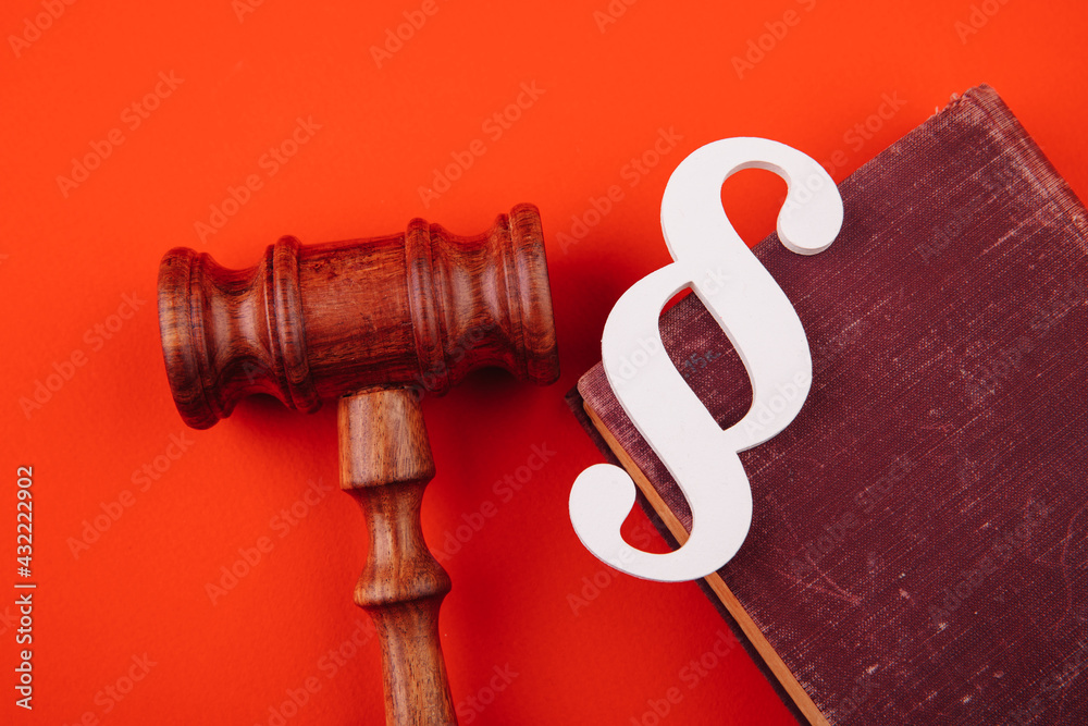 White paragraph symbol is on a law book and gavel on red background