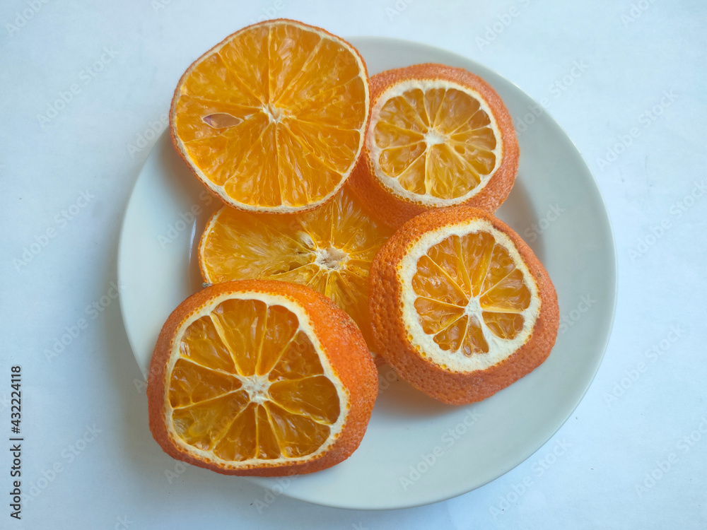 Fototapeta premium dried orange slices on a white saucer on a light background
