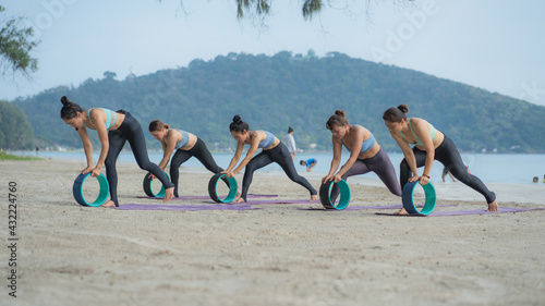 Asian women practicing yoga at the beach .