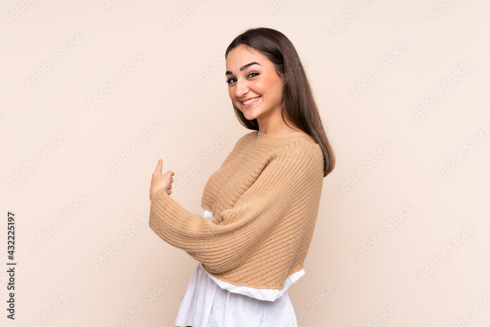 Young caucasian woman isolated on beige background pointing back Young caucasian woman isolated on beige background pointing back