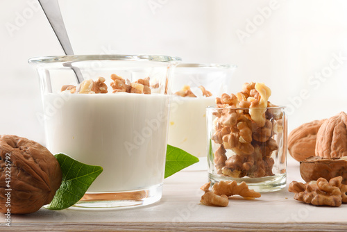 Yogurt with walnuts pieces in glass on wood bench