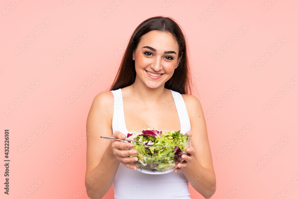 Young caucasian woman holding a salad isolated on pink background Young caucasian woman holding a salad isolated on pink background