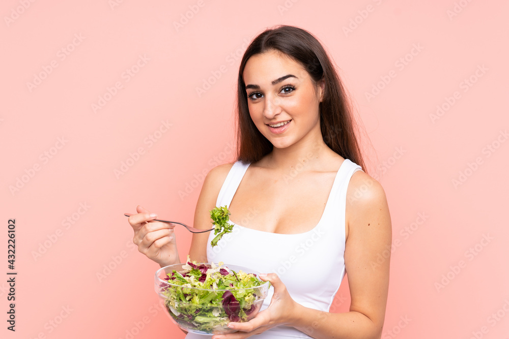 Young caucasian woman holding a salad isolated on pink background Young caucasian woman holding a salad isolated on pink background